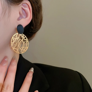 Detail von Vintage-Ohrringen mit schwarzem Stecker und goldenen hohlen geometrischen Anhängern