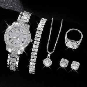Close-up of sparkling silver watch and jewelry set with crystals on black background