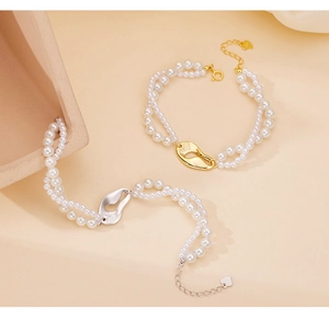 Dettaglio di bracciali a chicchi di caffè in argento 925 con perle bianche e ciondolo cuore