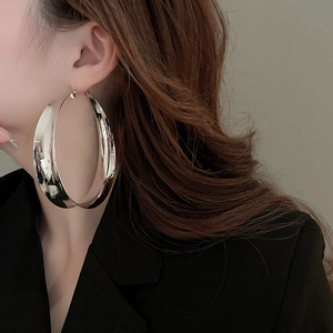 Side view of large silver hoop earrings worn by a model to show mirror-finish metal texture