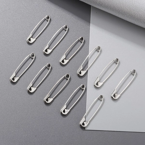 Group of eleven silver plated metal safety pins for garments on a clean background