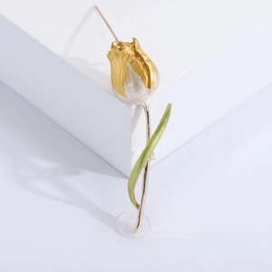 Elegant tulip brooch with white enamel petals and green leaves on white podium