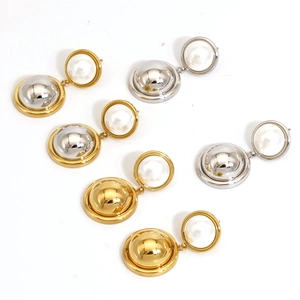 Détail de boucles d'oreilles boules en métal bicolore avec perles blanches