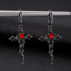Detail view of Gothic thorn cross earrings with a red heart gem and dark gunmetal finish