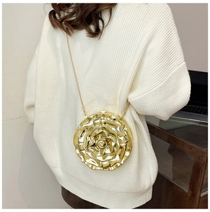 Detail view of a rose shaped gold metallic chain bag worn by a model from the back