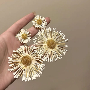 Close-up of model wearing large white and gold daisy flower earrings in a stylish design