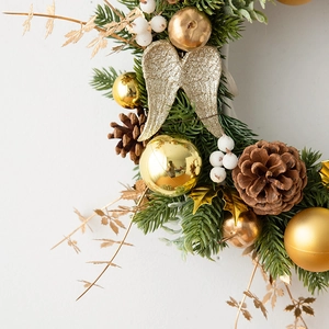 Christmas wreath detail with gold ornaments, pine cones and decorative angel wings