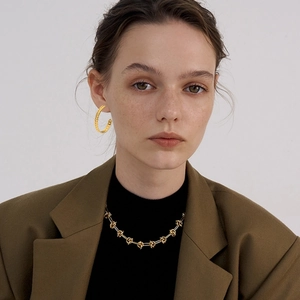 Detailed close-up of 18K gold plated chunky chain hoop earrings and necklace on a model