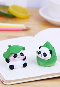 Close-up of cute resin pandas in bamboo shoot and leaf hats on a desk workspace