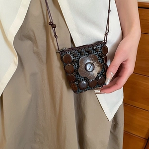 Detail of handmade mini wood coconut shell bag featuring a large flower wood buckle