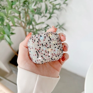 Close-up of hand holding a sparkling AirPods case set with multi-color rhinestones