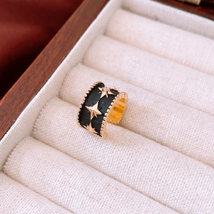 Close-up of black and gold ring with star patterns in a velvet jewelry box