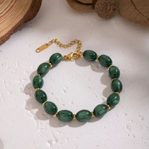 Detail of dark green resin beaded bracelet with gold accents on natural rustic background