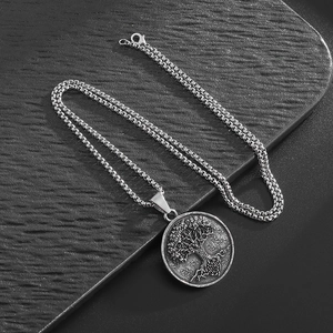 Vintage silver Tree of Life pendant necklace with box chain on dark textured background