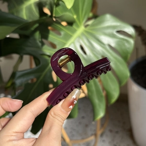 Close-up of elegant burgundy hair claw clip with glossy finish and gold metal spring