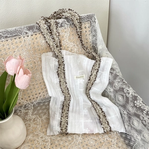 Détail de broderie florale sur un sac en toile blanc avec poignée tressée et étiquette Sozakka