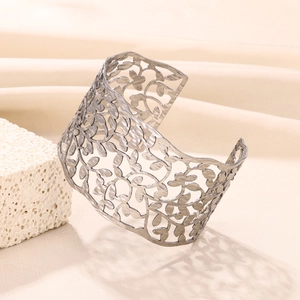 Detailed close-up of wide open bangle with hollow leaf patterns and matte metal texture