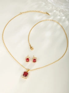 Macro detail of red gemstone necklace and earrings set with gold-plated metal finish