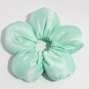 Macro shot of mint green oversized satin flower scrunchie with silky smooth texture