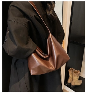 Side view of dark brown leather tote bag worn by model showing its flexible silhouette