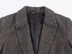 Detailed view of grey-brown herringbone wool blazer with notch lapel and black silk lining