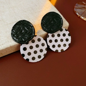 Close-up of vintage black and white polka dot acrylic stud earrings on a book