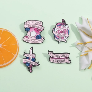 Set of four creative pink enamel sword pins with motivational English quotes on green background