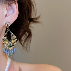 Close-up of vintage tassel earrings with green crystals and iridescent beads on model