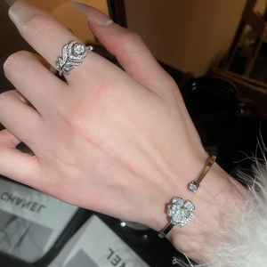Dettaglio del bracciale a fiori in zircone e anello a piuma in argento per uno stile elegante