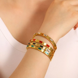 Bracelets en acier doré sertis de zircons rectangulaires colorés portés par un mannequin