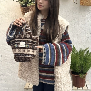 Plush faux shearling tote bag with ethnic stripes and floral embroidery held by model