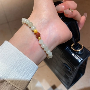 Détail d'un bracelet en perles de jade Hetian avec ambre et perles dorées au poignet