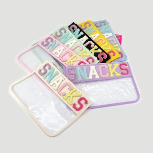 Detail of waterproof PVC travel bags with colorful SNACKS chenille patches and metal zippers