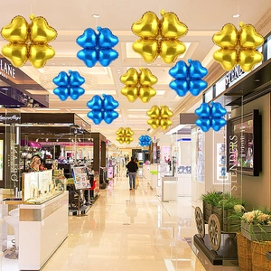 Detail of clover-shaped heart foil balloons in gold and blue hanging for mall decoration