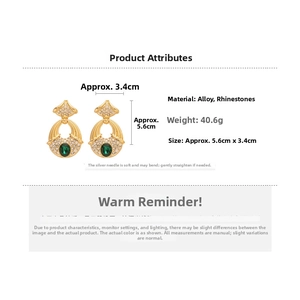 Détail de boucles d'oreilles vintage dorées avec gemmes vert émeraude et cristaux