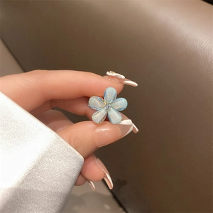 Macro shot of a light blue pearlescent flower hair claw with a crystal center detail