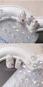 Detailed view of bubble heart aurora nail art stickers on white nail tips with 3D beads