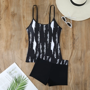 Flat lay of a two-piece tankini swimsuit with vertical tie-dye print on a wood background
