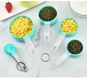 Top view of green and stainless steel measuring cups and spoons set on marble