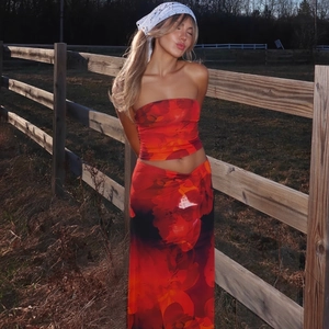 Détail d'un ensemble jupe longue et haut bandeau rouge à fleurs sous la lumière dorée