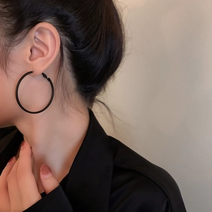 Close-up of minimalist black matte hoop earrings worn by a model for a stylish look