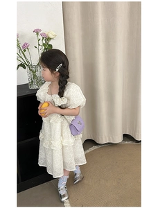 Detail view of a purple quilted chain crossbody bag paired with a white ruffled dress