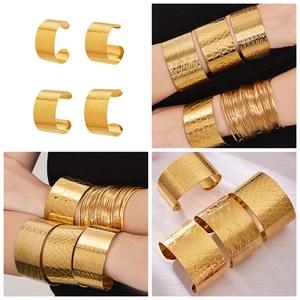 Détails de bracelets manchettes dorés avec des motifs alvéolés et floraux ciselés