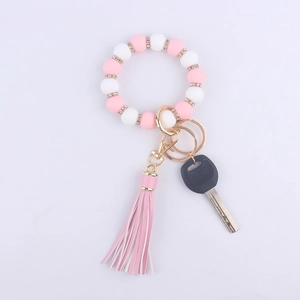Detail of pink and white silicone beaded keychain bracelet with faux leather tassel