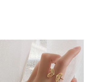Close-up of a hollow carved gold butterfly wing ring on a model hand with soft light