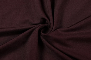 Dettaglio macro del tessuto a maglia bordeaux scuro con lucentezza setosa e trama fine