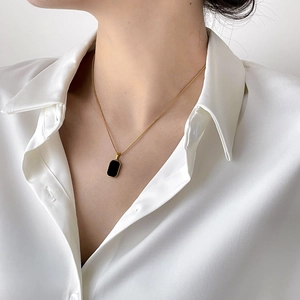 Minimalist double layer gold necklace with square black onyx pendant on a female model