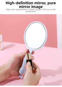 Close-up of a handheld makeup mirror with a cartoon relief handle and a black gold lipstick