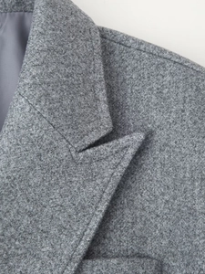 Dettaglio di un cappotto di lana grigio che mostra il classico bavero e le cuciture