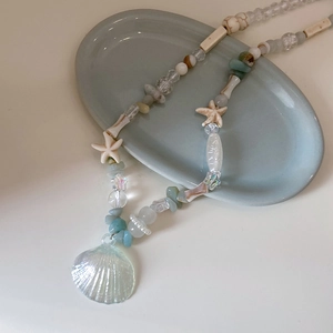 Detail of beaded necklace with iridescent shell pendant and starfish beads on tray